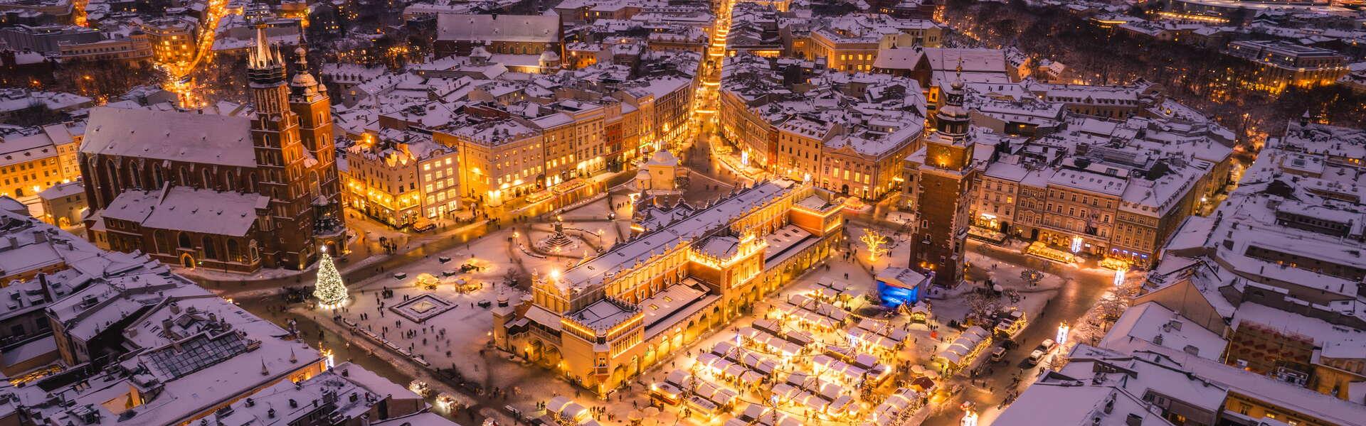 Ein Blick aus der Vogelperspektive auf das verschneite Kraków und den Weihnachtsmarkt auf dem Hauptmarkt.