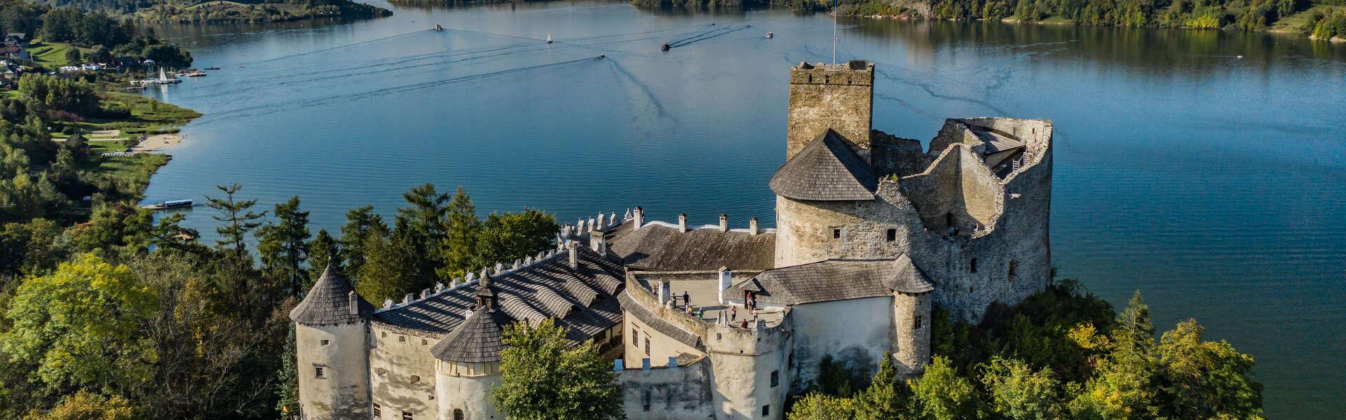 Widok na Zamek Dunajec w Niedzicy z lotu ptaka. W tle Jezioro Czorsztyńskie oraz lasy. Z lewej przestań dla żaglówek.