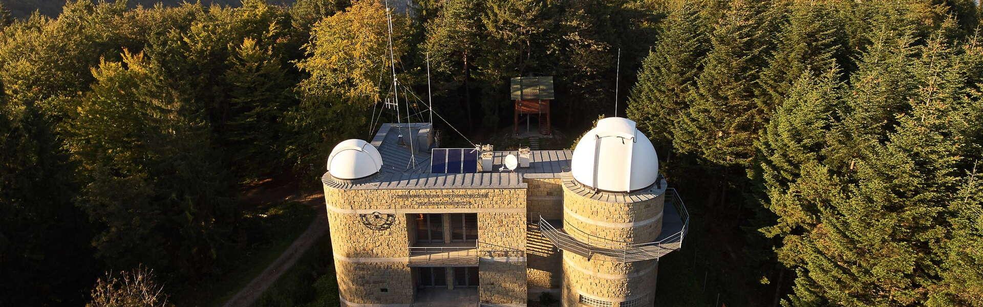 Wieczorny krajobraz leśny z budynkiem obserwatorium astronomicznego.