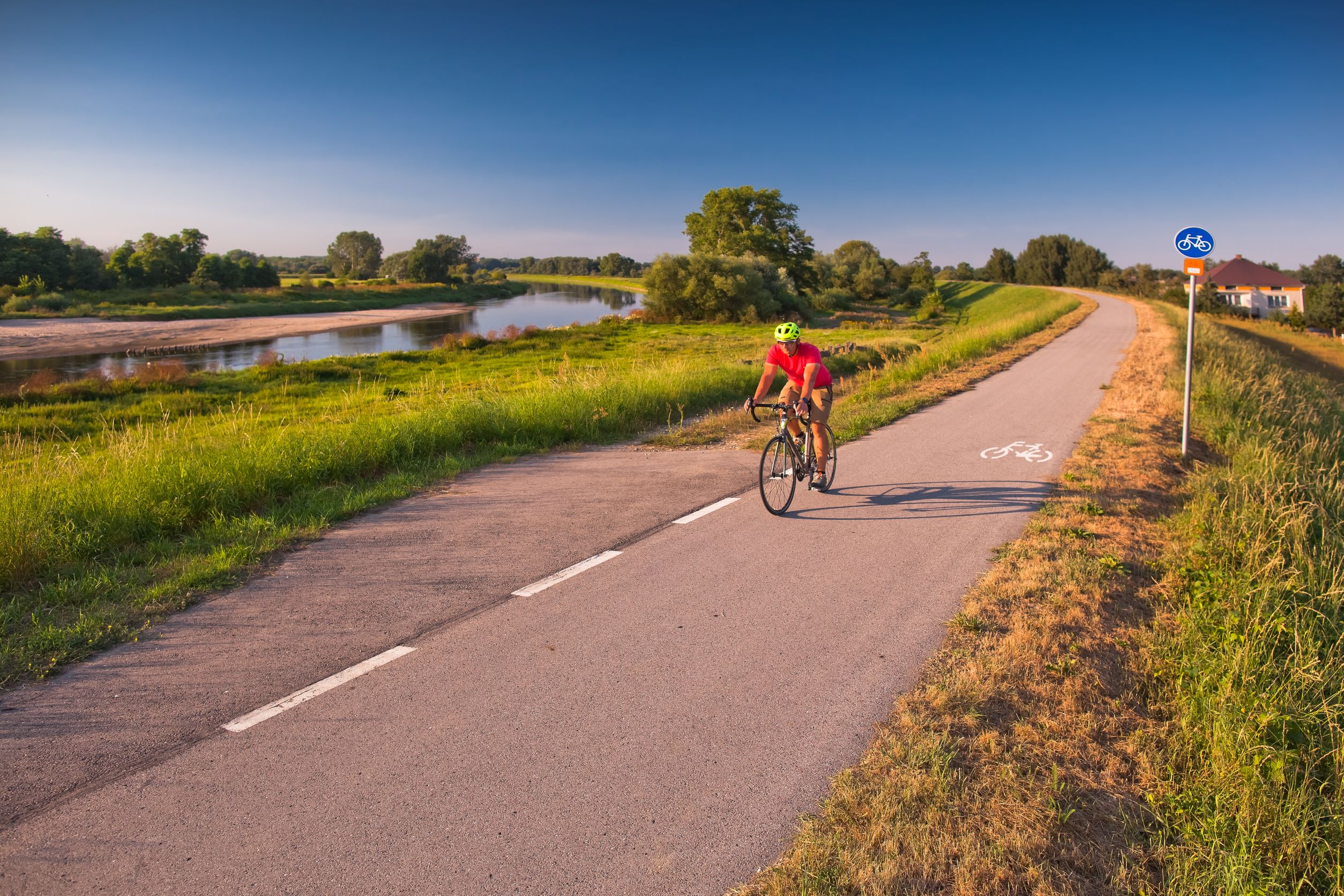 Rowerzysta jedzie po ścieżce rowerowej wzdłuż rzeki